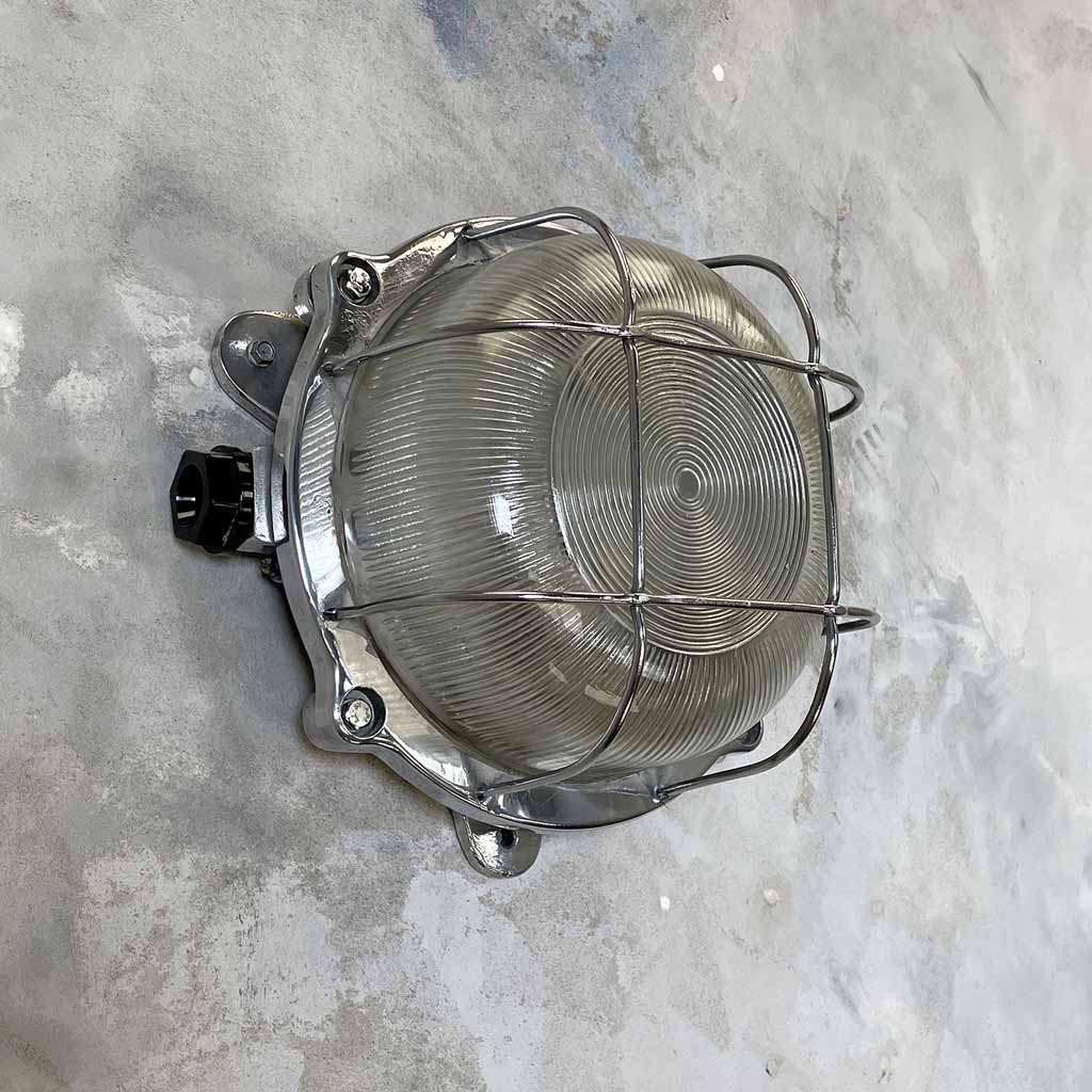 Vintage industrial circular aluminium outdoor bulkhead wall light with prismatic glass and protective cage, can also be used as indoor wall lighting. 
