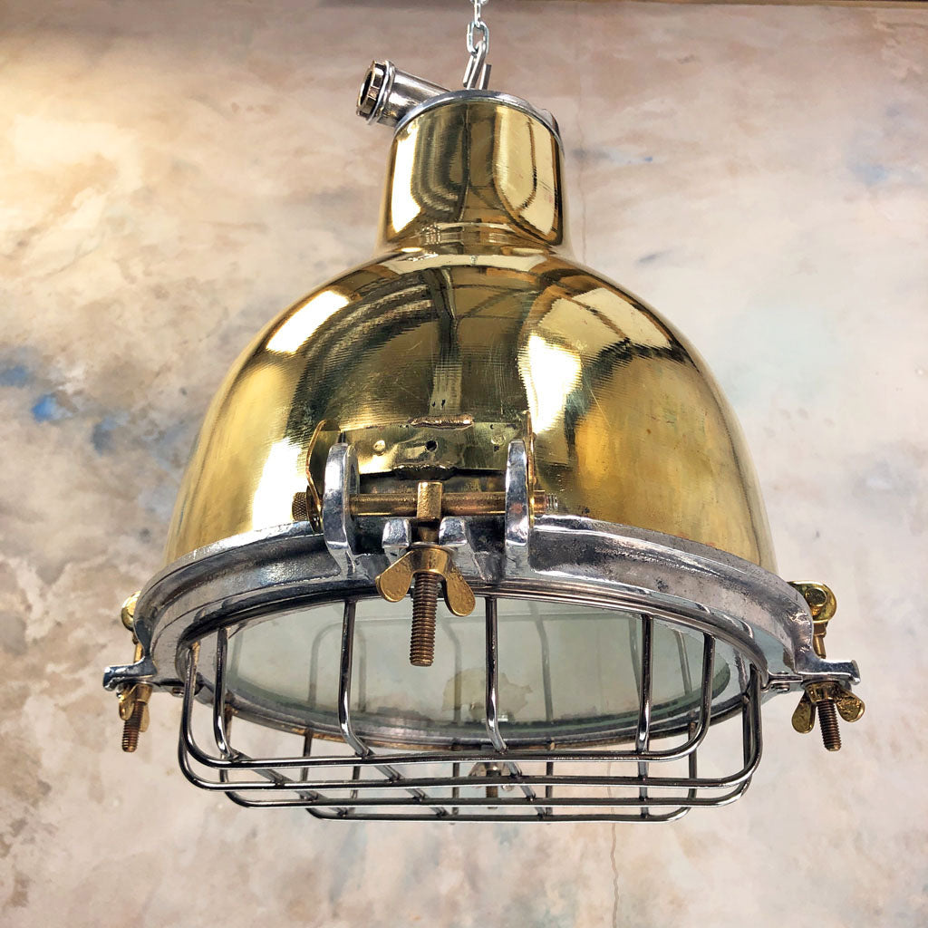 A vintage brass dome ceiling pendant light fixture with an aluminium industrial style cage. 