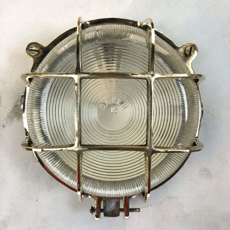 a vintage brass circular bulkhead wall light with prismatic glass shade and industrial cage