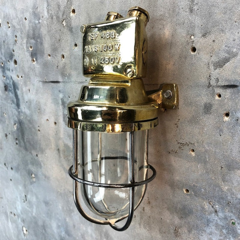 A retro industrial brass outdoor wall light with protective glass shade and cage