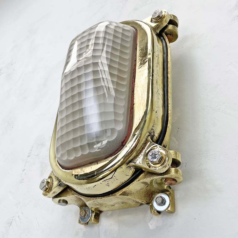 Vintage industrial brass bulkhead wall light with a frosted glass cover. The frosted glass cover has a decorative quadrant pattern which softens the illumination making it a unique industrial style wall light.