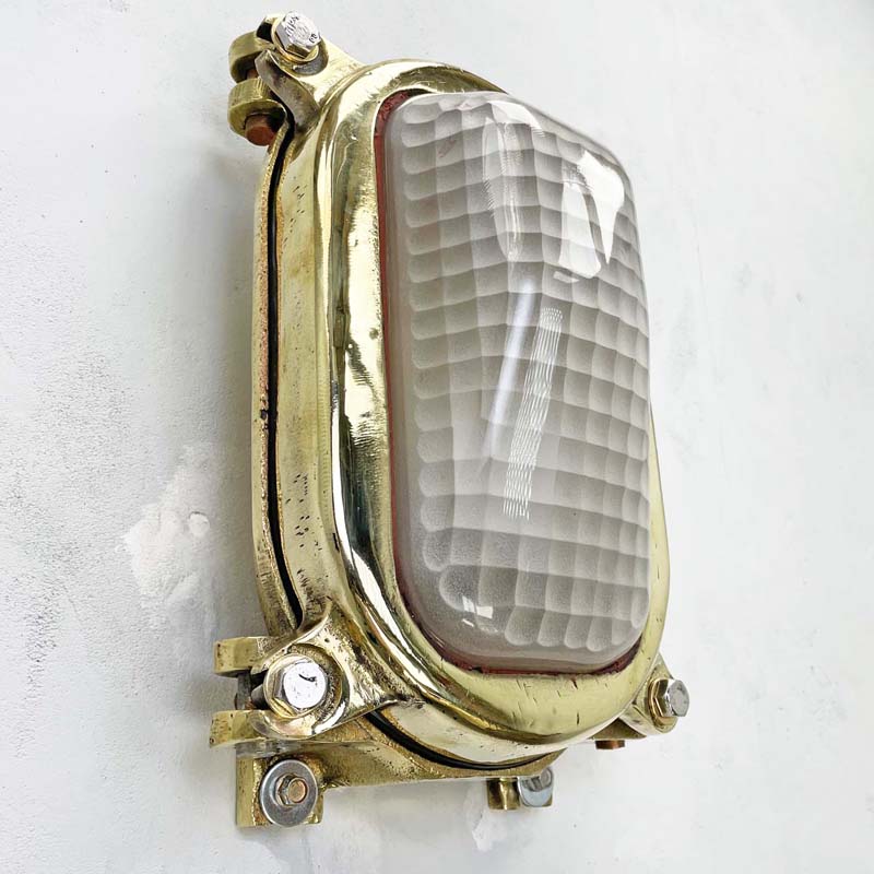 Vintage industrial brass decorative bulkhead wall light with a frosted glass cover. The frosted glass cover has a quadrant pattern which softens the illumination making it a unique industrial style wall light.