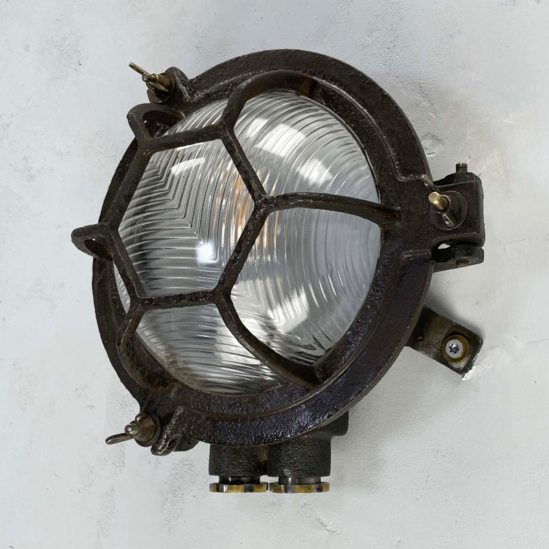 Black iron wall light with cage and prismatic glass cover. The round bulkhead is reclaimed and restored for modern interiors compatible with LED light bulb. 
