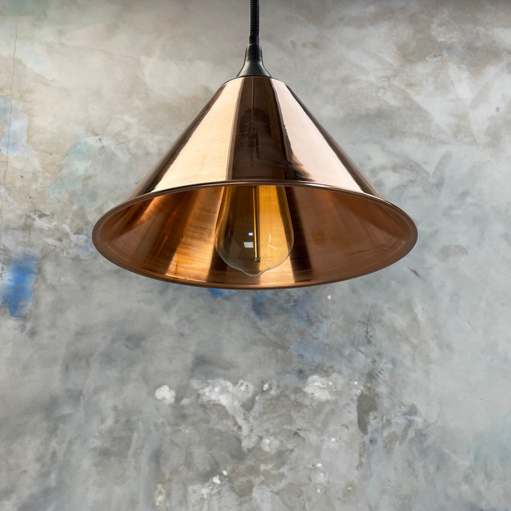 Small copper conical pendant lighting with black braided cable.