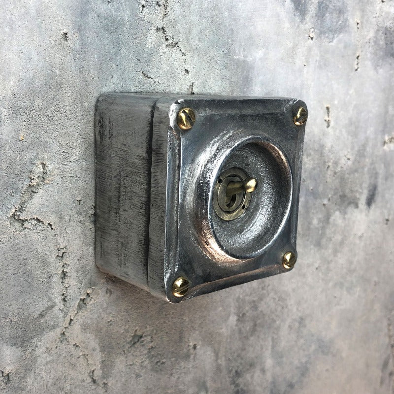 A single industrial light switch.  Manufactured from recycled alloy wheels.