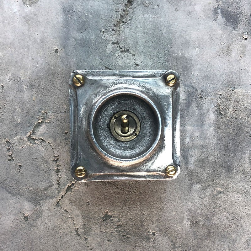 A single industrial light switch.  Manufactured from recycled alloy wheels.