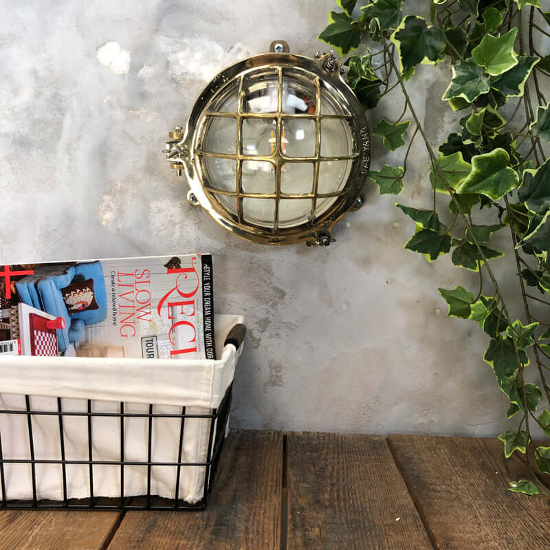 Vintage industrial brass circular bulkhead wall lighting with a protective cage by Daeyang. 
