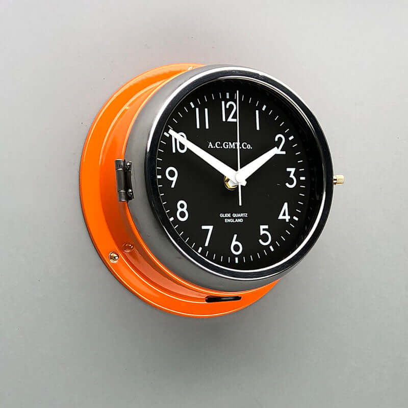A non-ticking orange nautical style wall clock with black face, reclaimed and restored by AC.GMT.Co. 