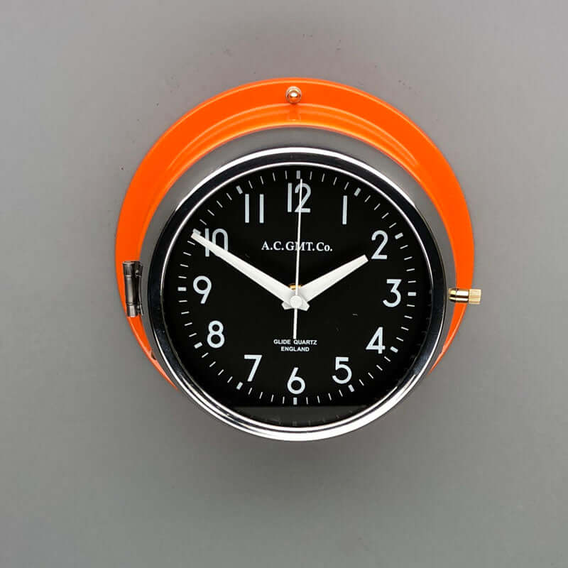 A non-ticking orange nautical style wall clock with black face, reclaimed and restored by AC.GMT.Co. 