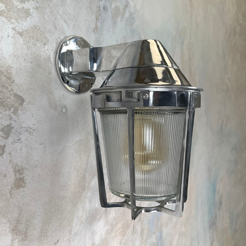A vintage cast aluminum wall light with prismatic glass shade and industrial style protective cage by Appleton