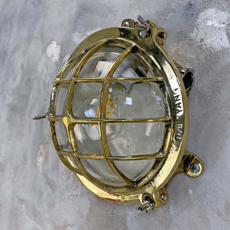 Vintage industrial brass circular bulkhead wall lighting with a protective cage by Daeyang. 
