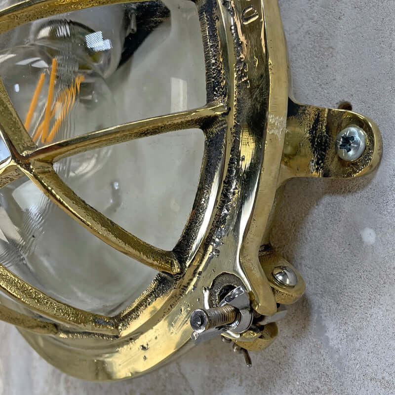 Vintage industrial brass circular bulkhead wall lighting with a protective cage by Daeyang. 