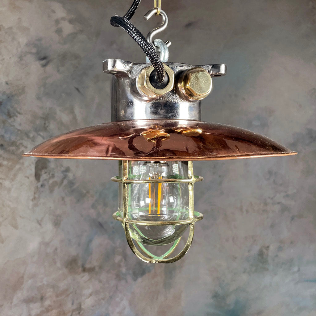 A reclaimed vintage industrial copper & iron explosion proof ceiling pendant light with a protective brass cage.