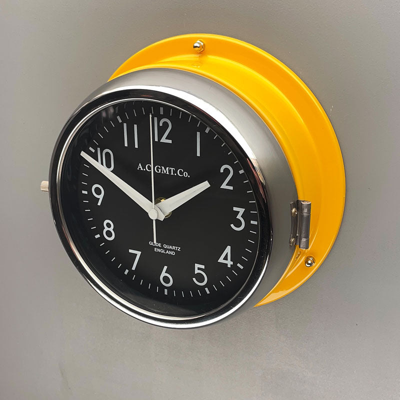 A silent yellow circular wall clock with black face, reclaimed and restored by AC.GMT.Co. 