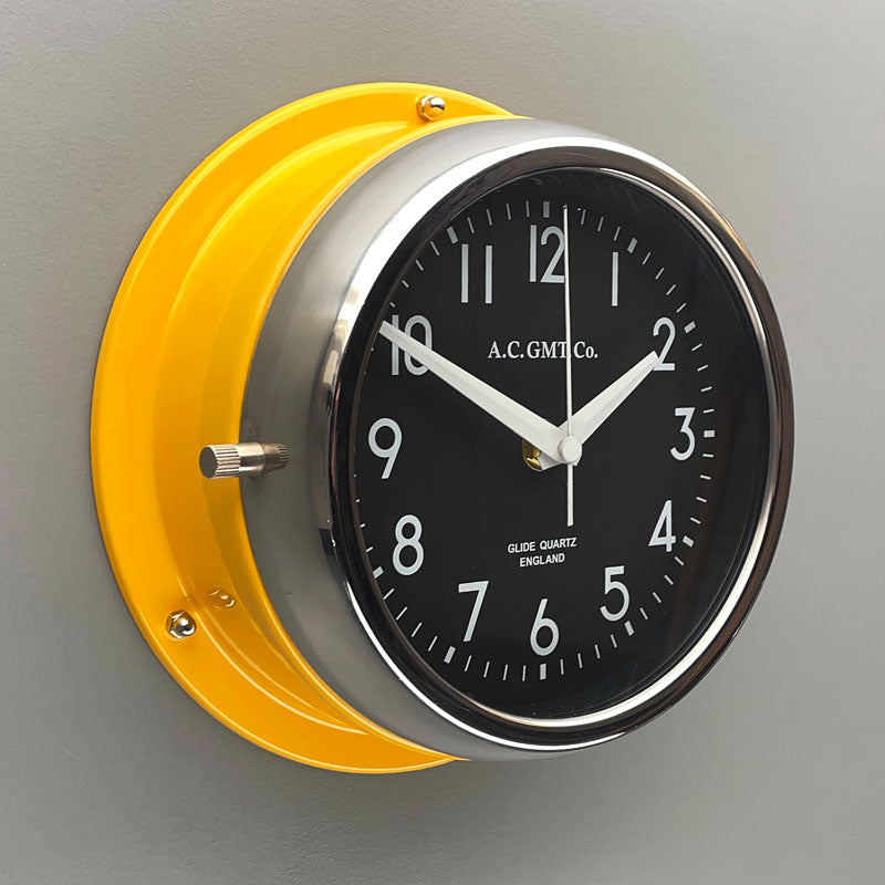 A silent yellow circular wall clock with black face, reclaimed and restored by AC.GMT.Co. 