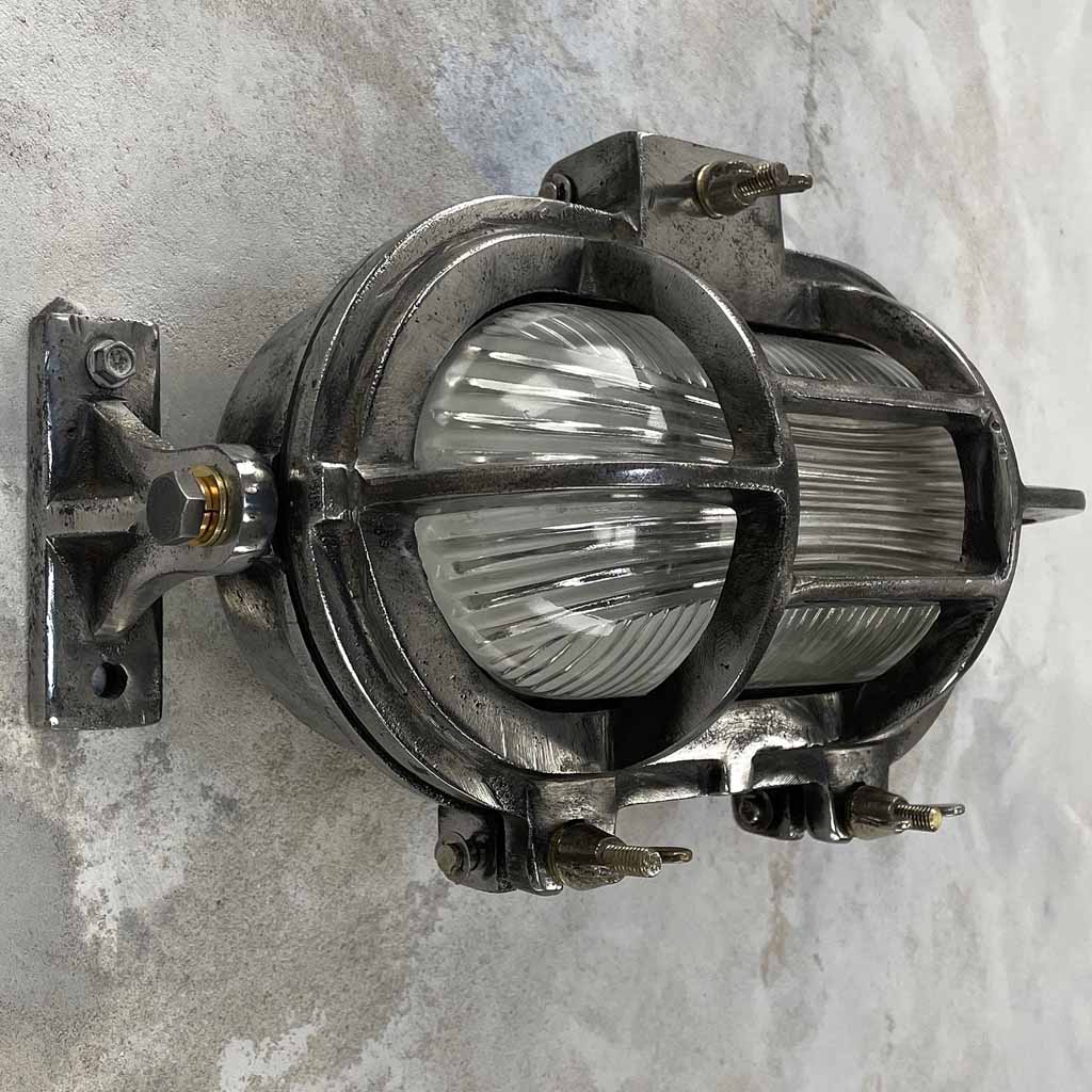 Industrial Style oblong bulkhead wall lighting with reeded glass and tilting feet which allows the fixture to be angled up and down when mounted horizontally, or left and right if mounted vertically. 