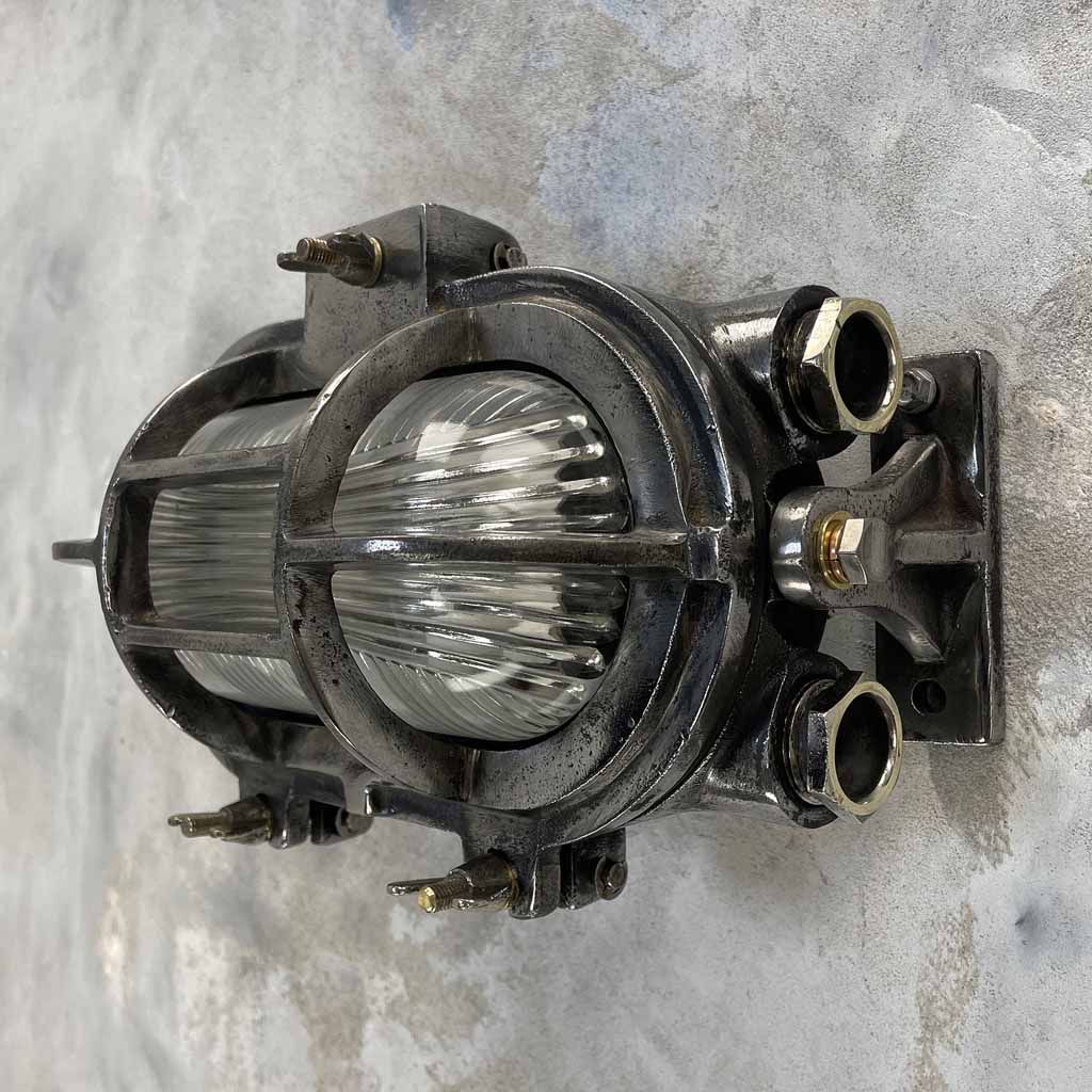 Industrial style cast iron oblong bulkhead wall lighting with reeded glass and tilting feet which allows the fixture to be angled up and down when mounted horizontally, or left and right if mounted vertically. 